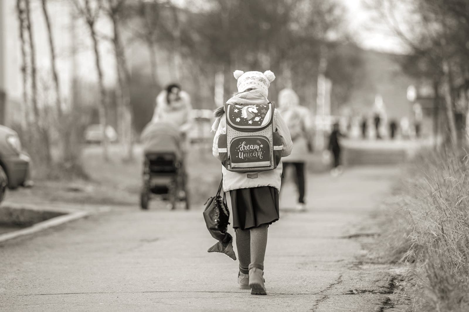 A child walking along a path to school wearing a backpack